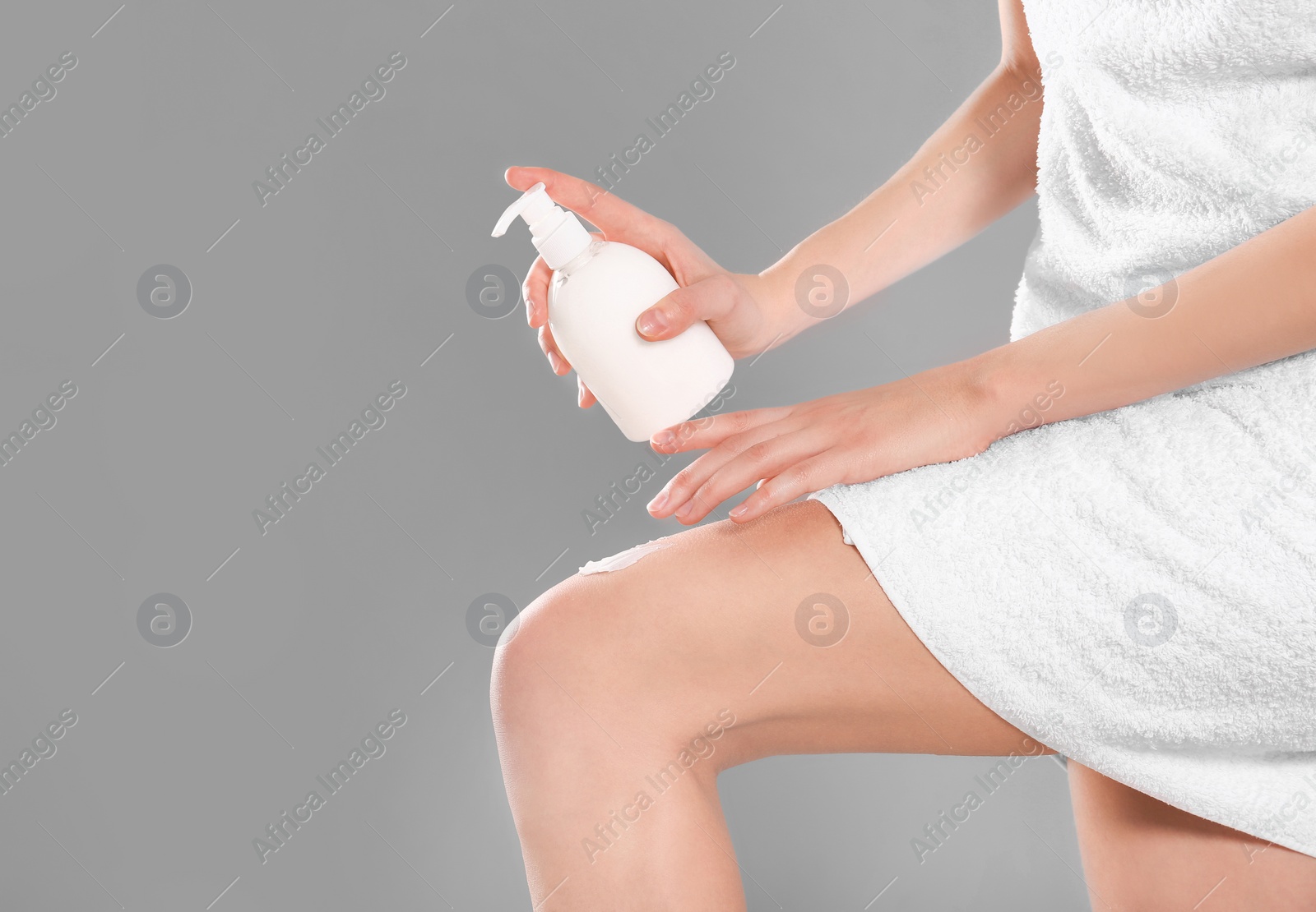Young woman with bottle of body cream on color background Photo of Young woman with bottle of body cream on color background