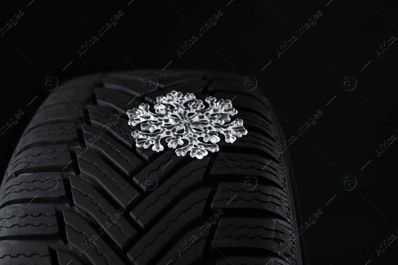 Winter tire with icy snowflake on black background, closeup Photo of Winter tire with icy snowflake on black background, closeup