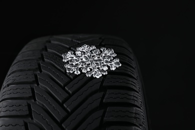 Winter tire with icy snowflake on black background, closeup Photo of Winter tire with icy snowflake on black background, closeup