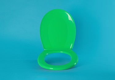 New green plastic toilet seat on light blue background, space for text Photo of New green plastic toilet seat on light blue background, space for text