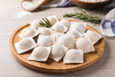 Uncooked ravioli and rosemary on white wooden table Photo of Uncooked ravioli and rosemary on white wooden table
