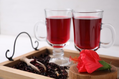 Beautiful Hibiscus flower and delicious tea on wooden tray, closeup Photo of Beautiful Hibiscus flower and delicious tea on wooden tray, closeup