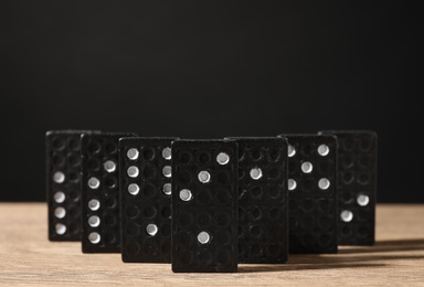 Domino tiles on wooden table against black background. Space for text Photo of Domino tiles on wooden table against black background. Space for text