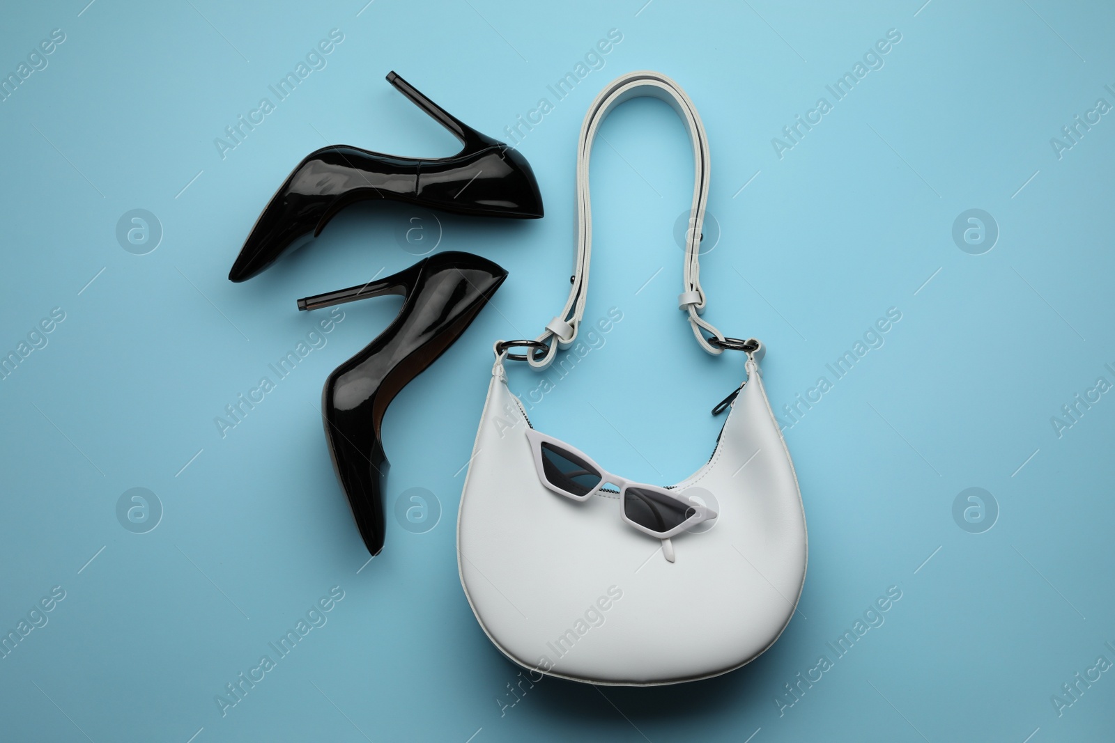 Stylish woman's bag, shoes and sunglasses on light blue background, flat lay Photo of Stylish woman's bag, shoes and sunglasses on light blue background, flat lay
