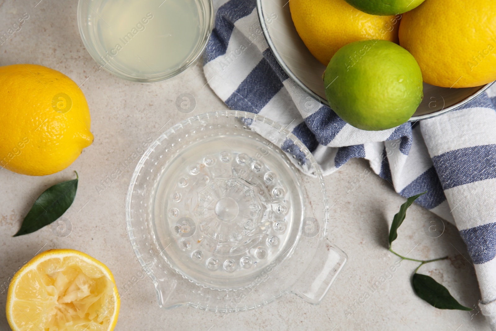 Glass squeezer with juice and lemons on light table, flat lay Photo of Glass squeezer with juice and lemons on light table, flat lay
