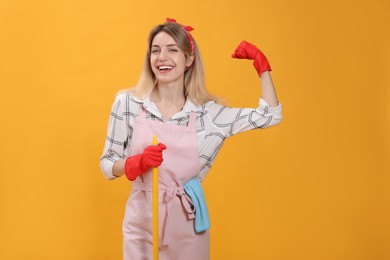 Young housewife with broom on yellow background Photo of Young housewife with broom on yellow background