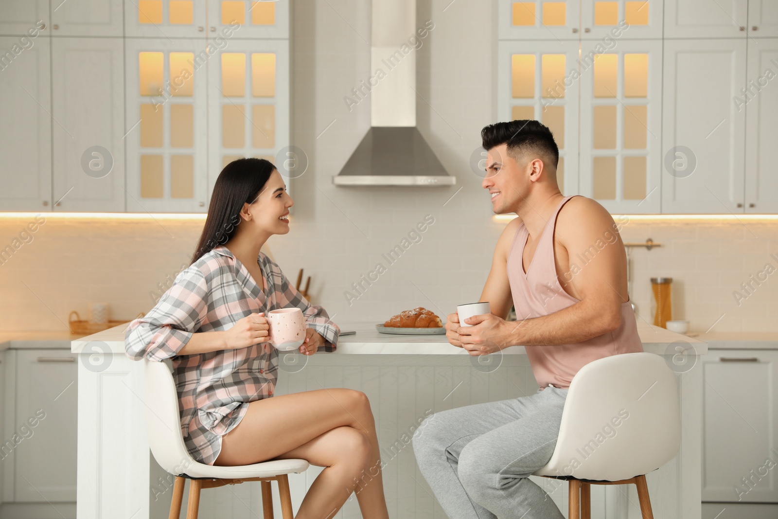 Happy couple wearing pyjamas during breakfast at table in kitchen Photo of Happy couple wearing pyjamas during breakfast at table in kitchen