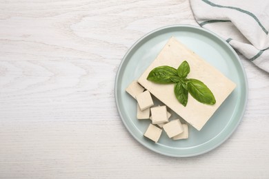 Delicious tofu with basil on white wooden table, top view. Space for text Photo of Delicious tofu with basil on white wooden table, top view. Space for text