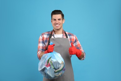 Man holding full garbage bag on light blue background Photo of Man holding full garbage bag on light blue background