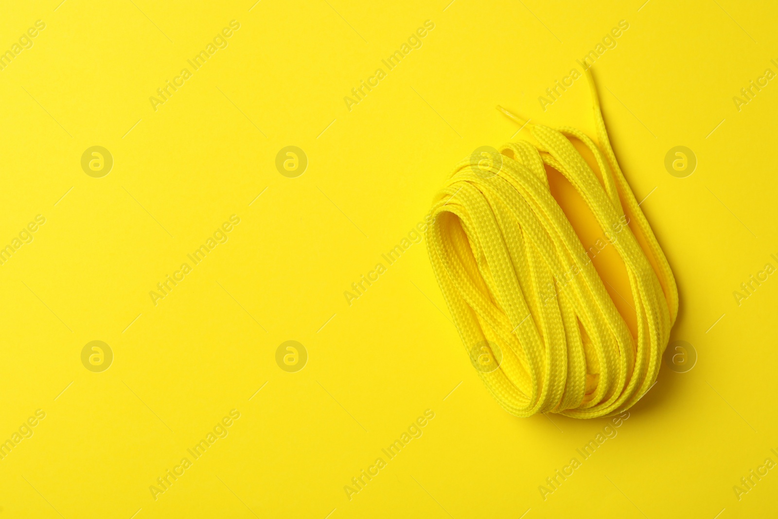 Shoelace on yellow background, top view. Space for text Photo of Shoelace on yellow background, top view. Space for text