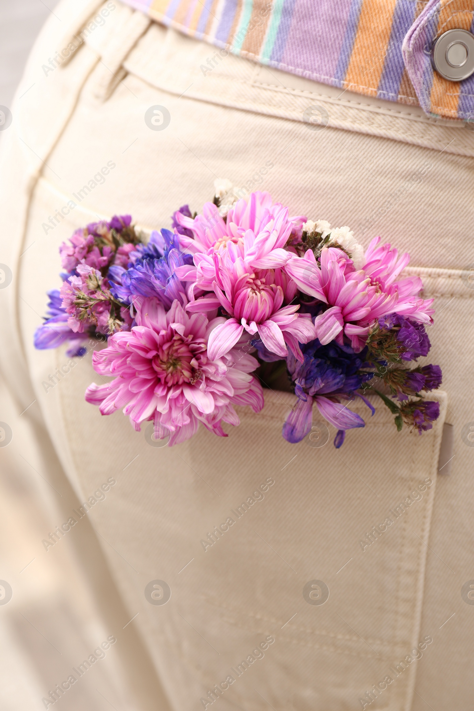 Woman wearing jeans with flowers in pocket, closeup Photo of Woman wearing jeans with flowers in pocket, closeup
