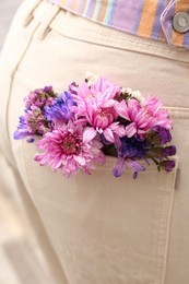 Woman wearing jeans with flowers in pocket, closeup Photo of Woman wearing jeans with flowers in pocket, closeup