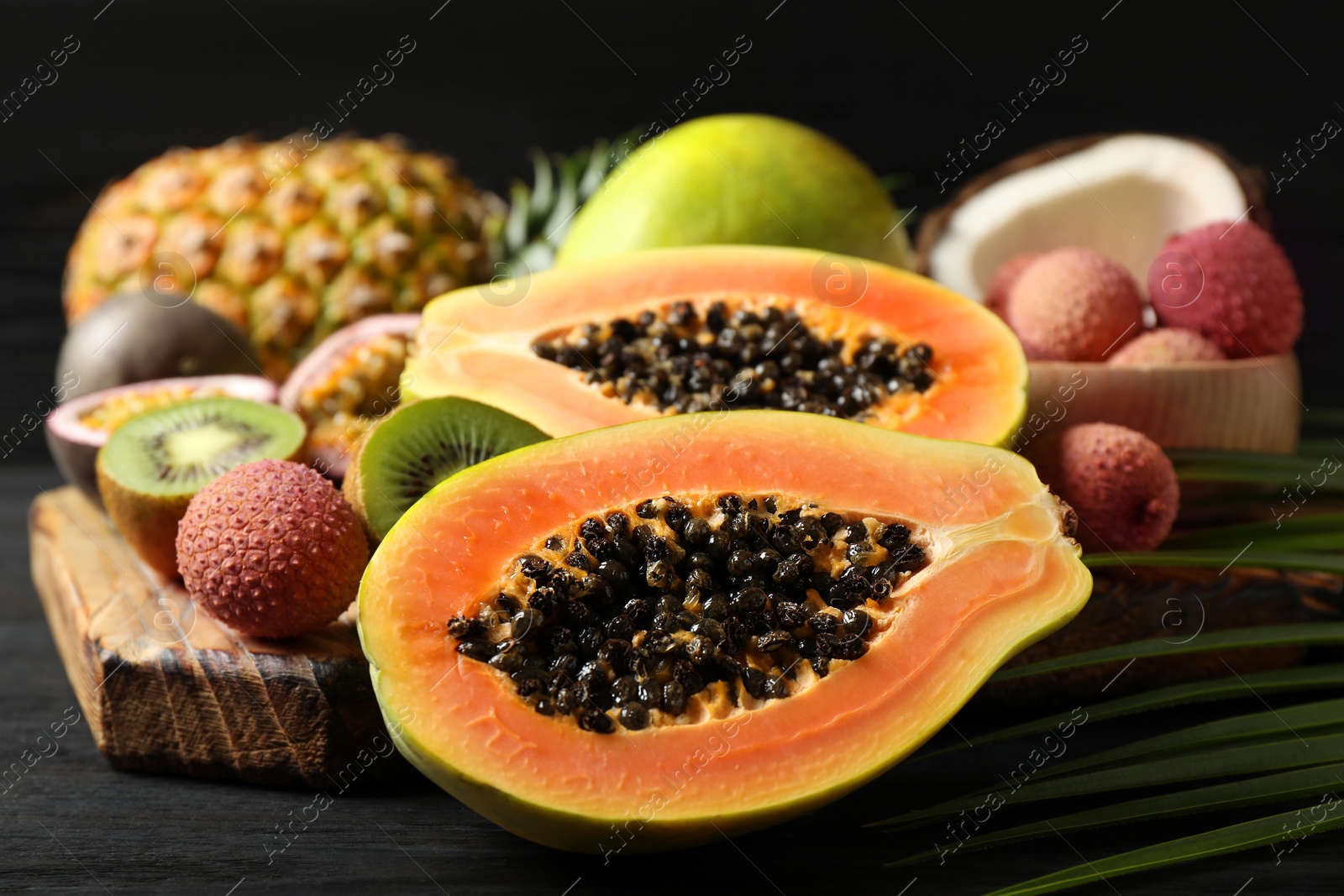 Fresh ripe papaya and other fruits on dark wooden table Photo of Fresh ripe papaya and other fruits on dark wooden table
