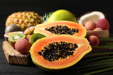 Fresh ripe papaya and other fruits on dark wooden table Photo of Fresh ripe papaya and other fruits on dark wooden table