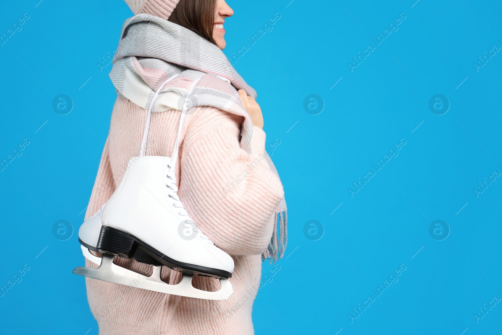 Happy woman with ice skates on light blue background, closeup. Space for text Photo of Happy woman with ice skates on light blue background, closeup. Space for text