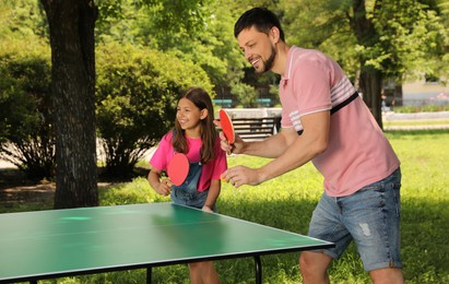 Happy man with his daughter playing ping pong in park Photo of Happy man with his daughter playing ping pong in park