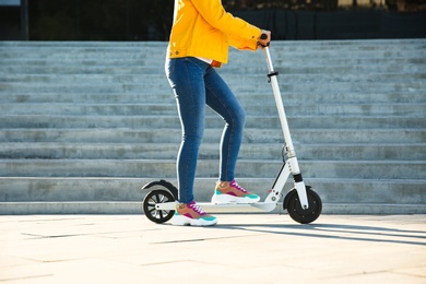 Woman riding electric kick scooter outdoors on sunny day Photo of Woman riding electric kick scooter outdoors on sunny day