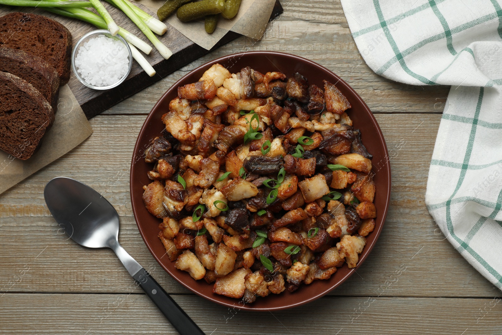 Tasty fried cracklings on wooden table, flat lay. Cooked pork lard Photo of Tasty fried cracklings on wooden table, flat lay. Cooked pork lard