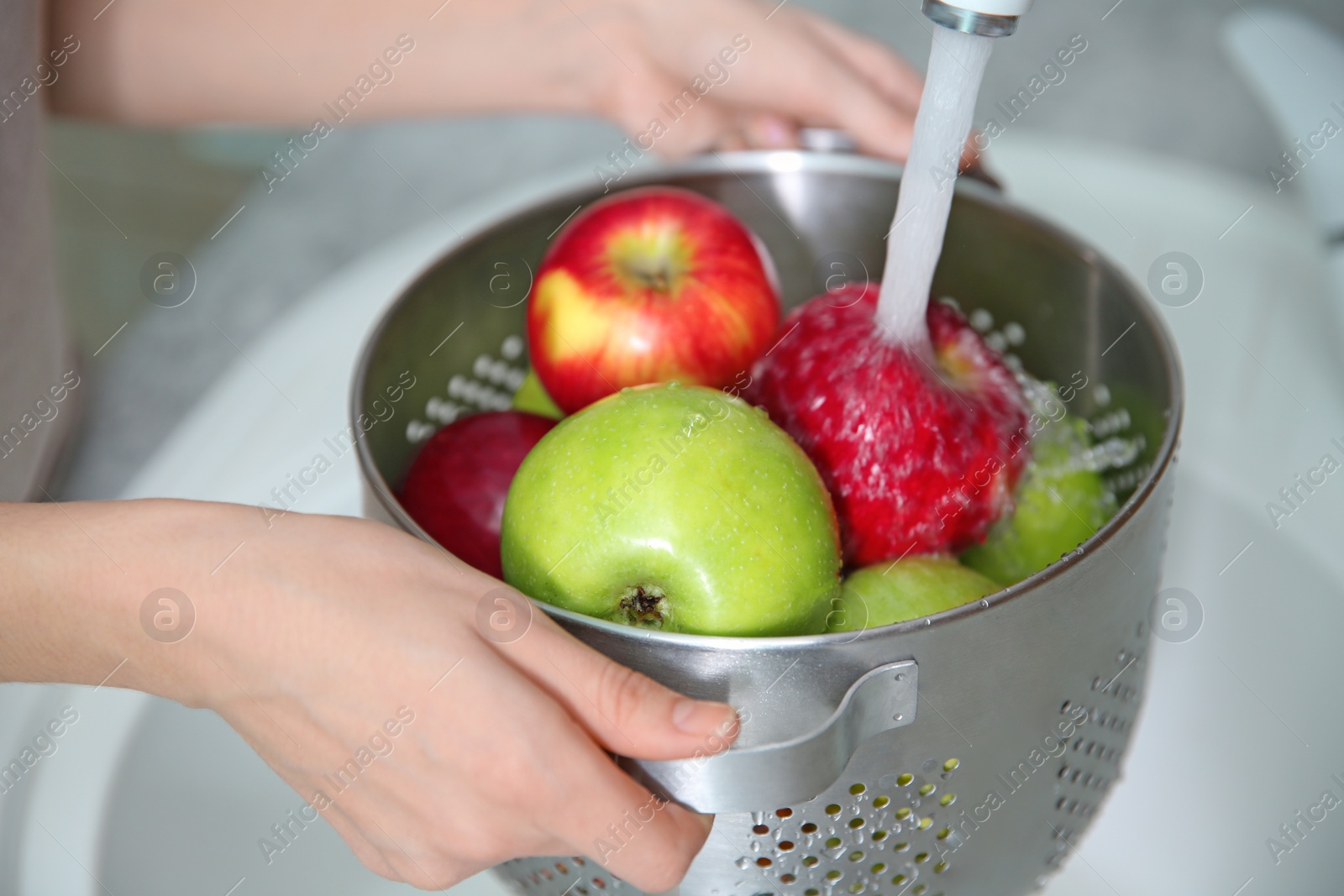 Young woman washing ripe apples in kitchen Photo of Young woman washing ripe apples in kitchen