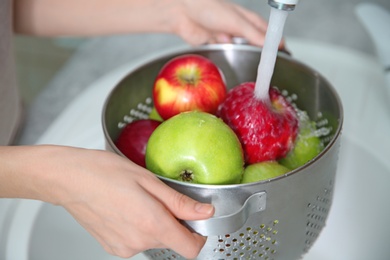 Young woman washing ripe apples in kitchen Photo of Young woman washing ripe apples in kitchen