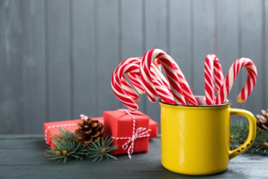 Many sweet candy canes in cup, gift boxes and Christmas decor on grey wooden table. Space for text Photo of Many sweet candy canes in cup, gift boxes and Christmas decor on grey wooden table. Space for text