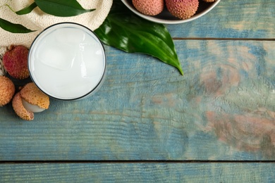 Photo of Fresh lychee juice and fruits on blue wooden table, flat lay. Space for text