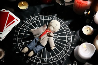 Voodoo doll pierced with needle surrounded by ceremonial items on table Photo of Voodoo doll pierced with needle surrounded by ceremonial items on table