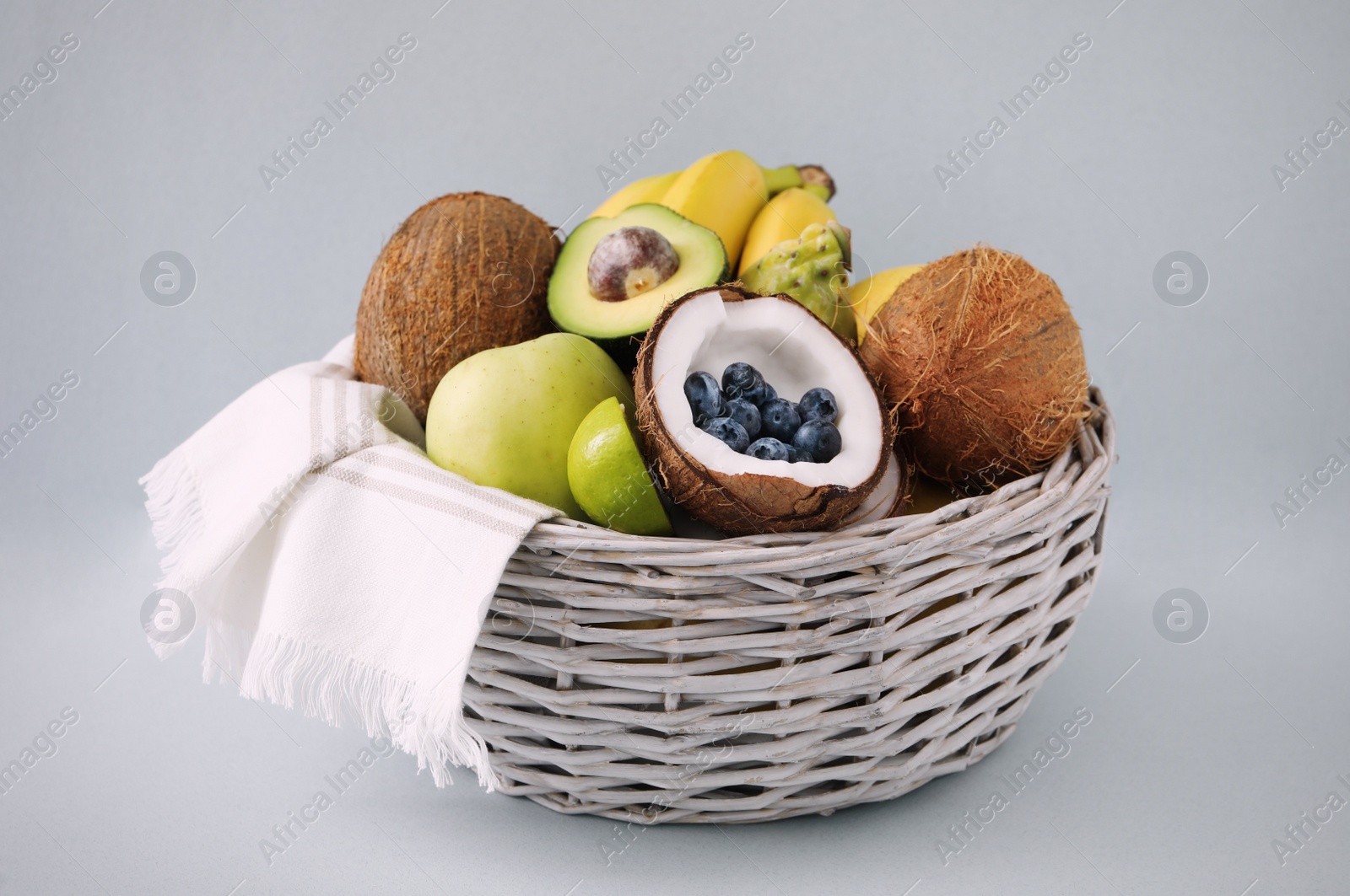 Assortment of fresh exotic fruits in basket on light background Photo of Assortment of fresh exotic fruits in basket on light background