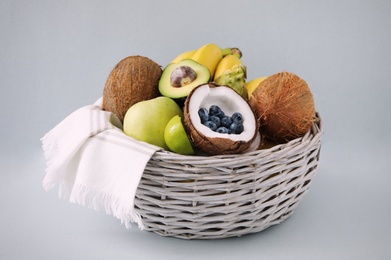 Assortment of fresh exotic fruits in basket on light background Photo of Assortment of fresh exotic fruits in basket on light background