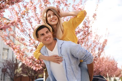 Happy stylish couple near blossoming sakura tree on city street. Spring family look Photo of Happy stylish couple near blossoming sakura tree on city street. Spring family look