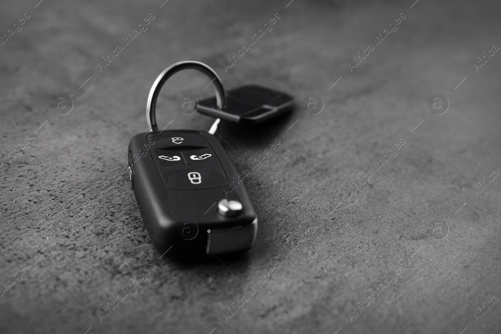 Modern car flip key with trinket on grey background. Space for text Photo of Modern car flip key with trinket on grey background. Space for text