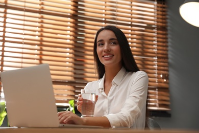 Young woman using laptop for search at wooden table in office Photo of Young woman using laptop for search at wooden table in office