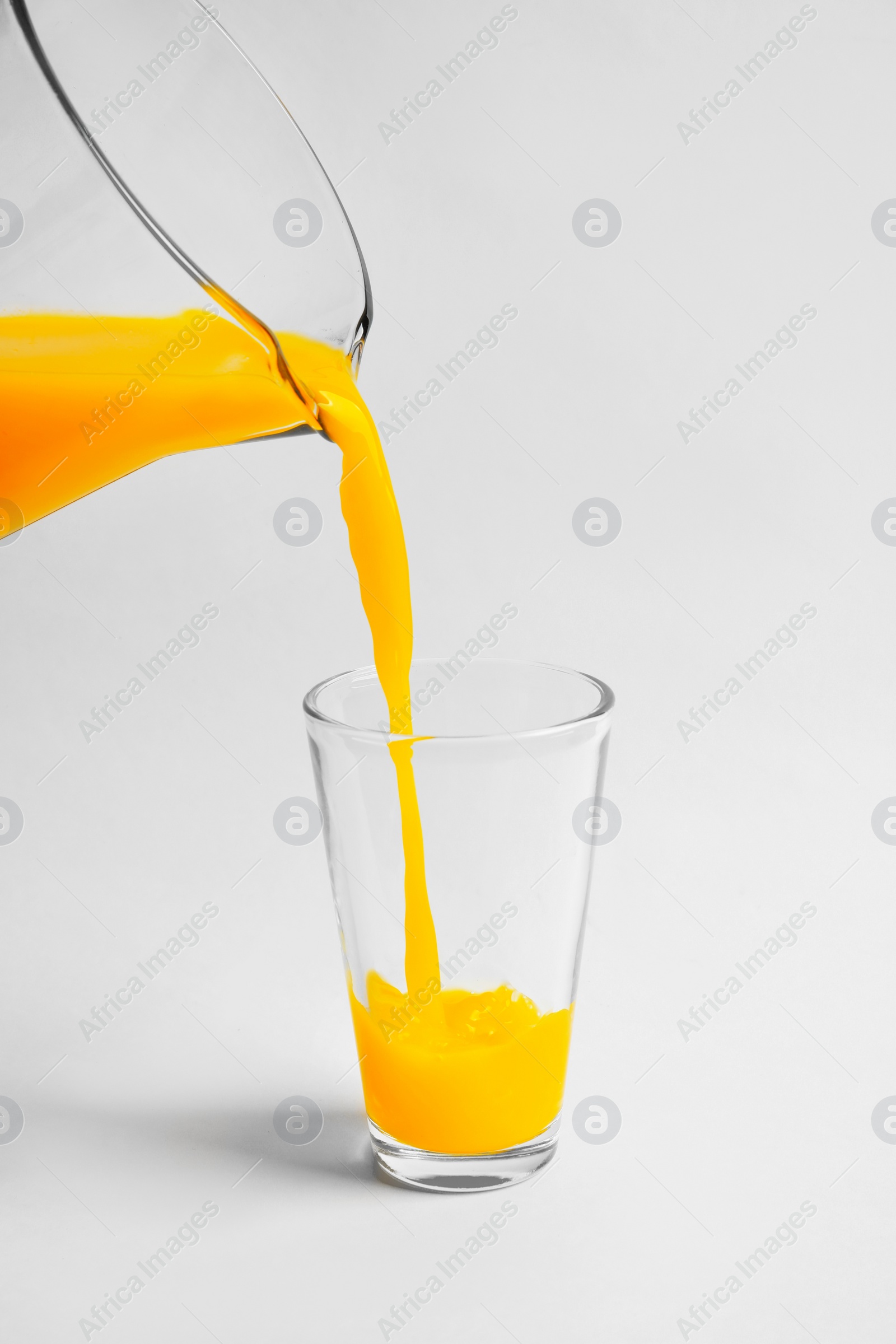 Pouring fresh orange juice into glass on white background Photo of Pouring fresh orange juice into glass on white background