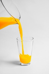 Pouring fresh orange juice into glass on white background Photo of Pouring fresh orange juice into glass on white background
