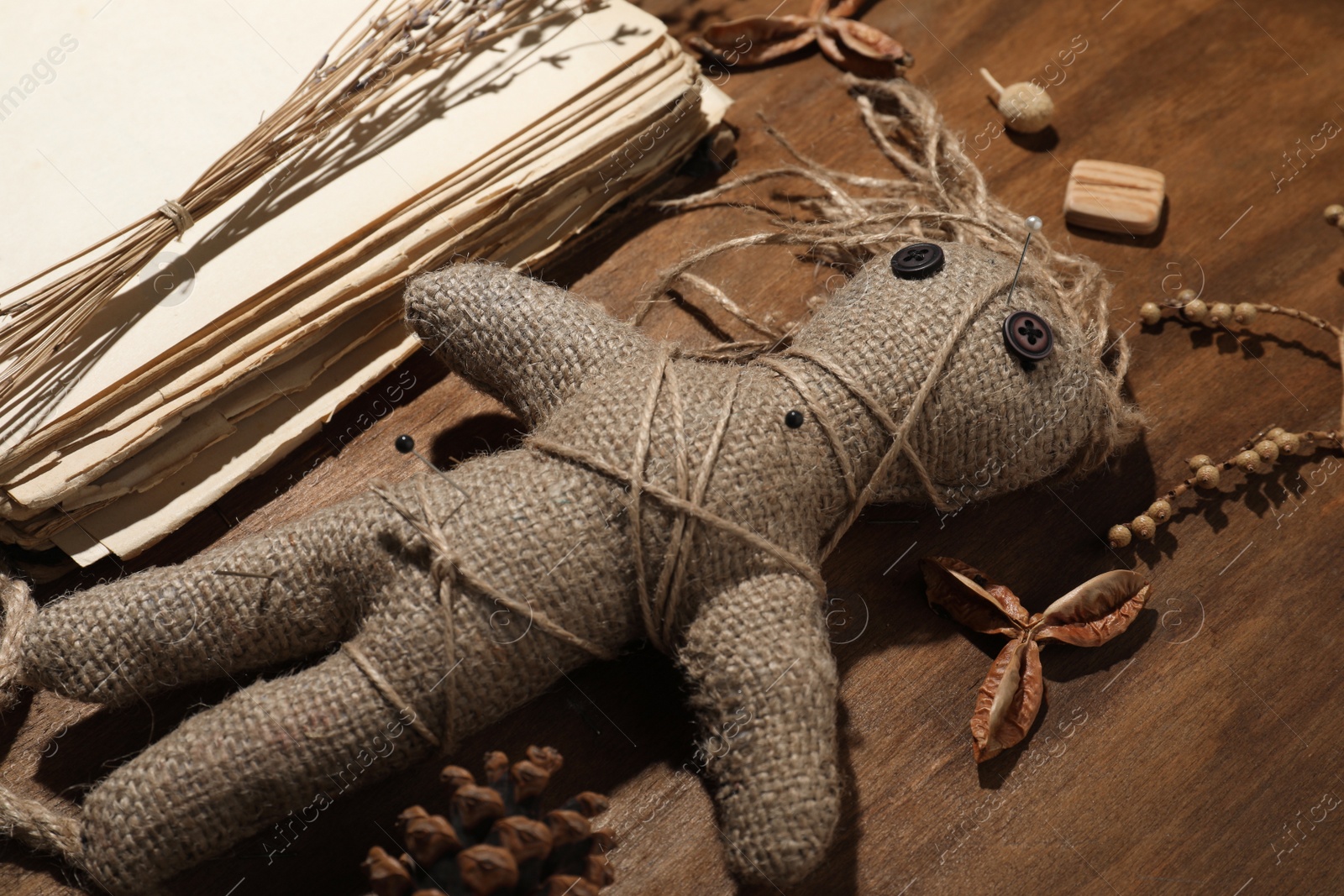 Female voodoo doll with pins surrounded by ceremonial items on wooden background, closeup Photo of Female voodoo doll with pins surrounded by ceremonial items on wooden background, closeup