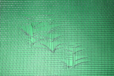 Torn window screen against green background, closeup Photo of Torn window screen against green background, closeup