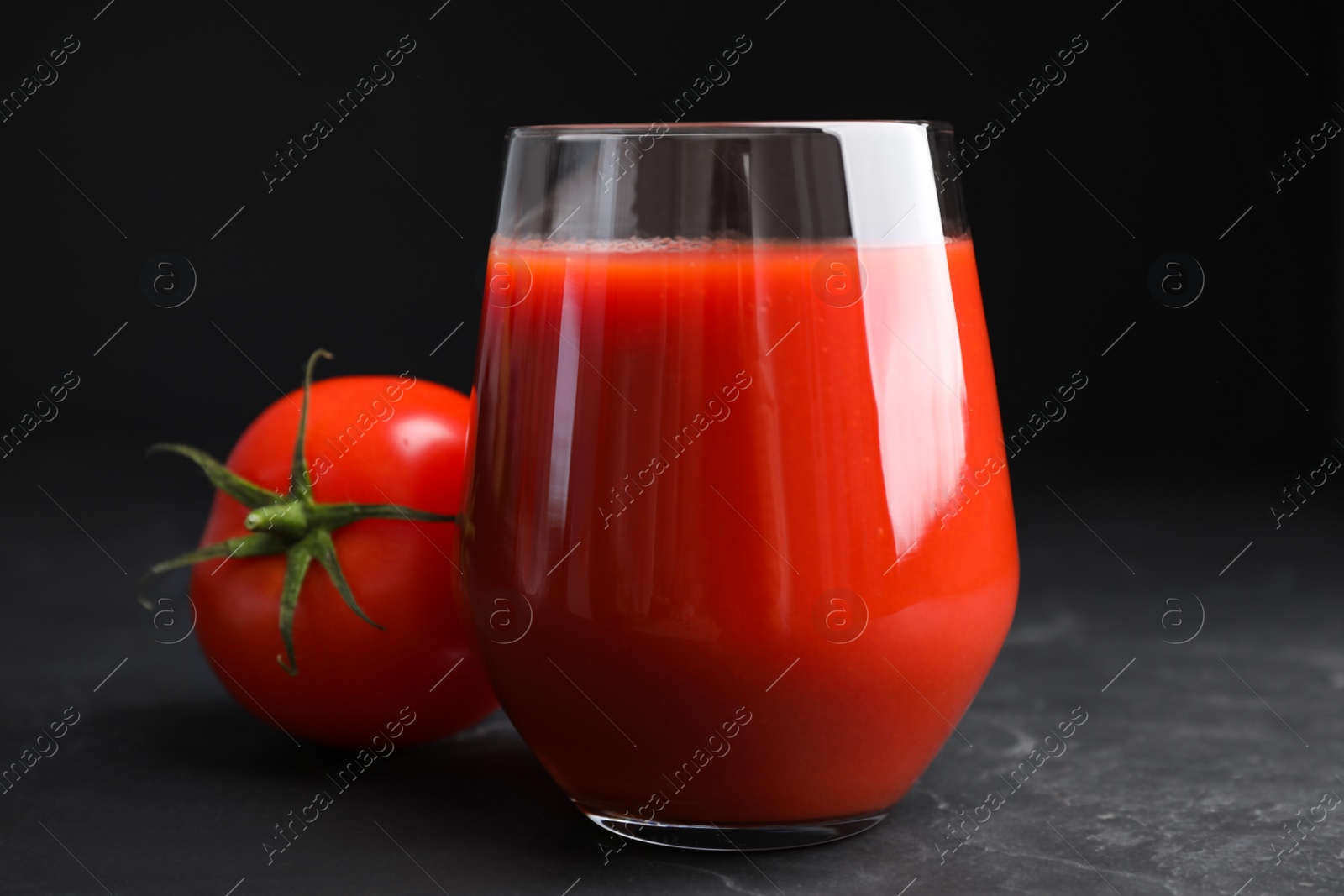 Photo of Delicious fresh tomato juice on black table, closeup