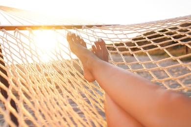 Young woman relaxing in hammock on beach at sunset, closeup Photo of Young woman relaxing in hammock on beach at sunset, closeup