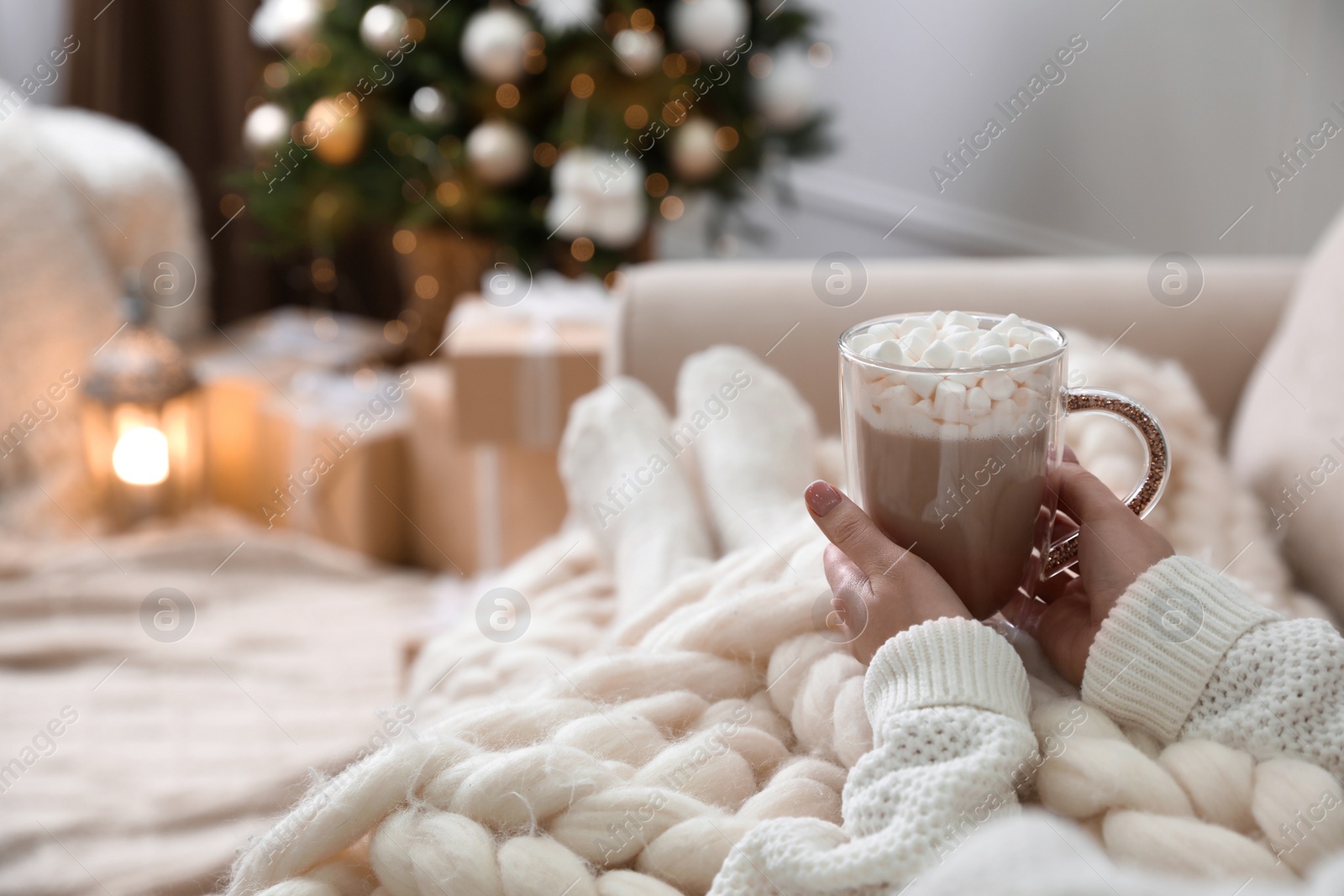 Woman with delicious hot drink wrapped in plaid on sofa at home, closeup. Space for text Photo of Woman with delicious hot drink wrapped in plaid on sofa at home, closeup. Space for text