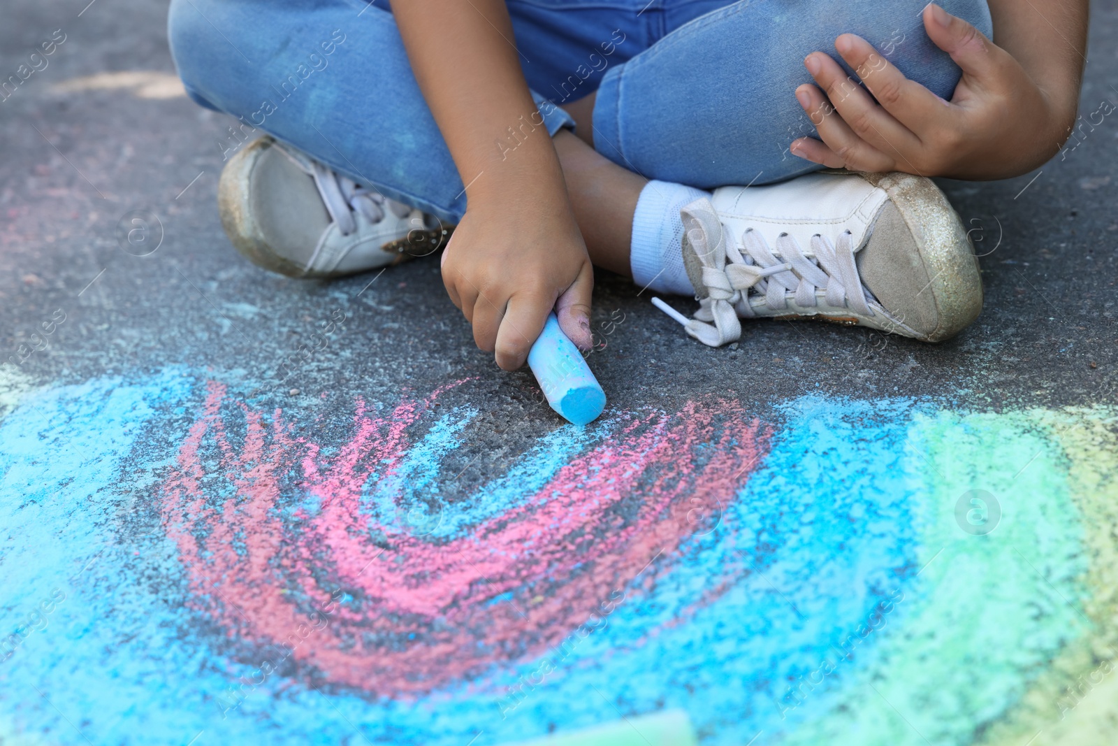 Little child drawing rainbow with colorful chalk on asphalt, closeup Photo of Little child drawing rainbow with colorful chalk on asphalt, closeup