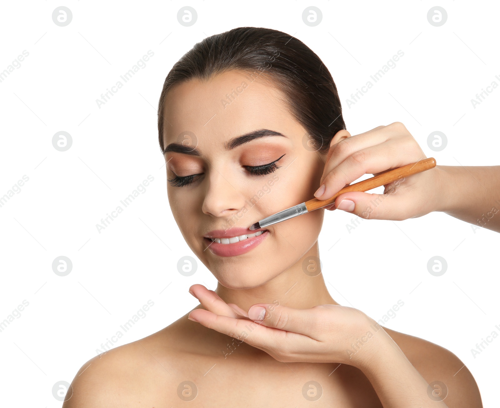Visage artist applying makeup on woman's face against white background. Professional cosmetic products Photo of Visage artist applying makeup on woman's face against white background. Professional cosmetic products