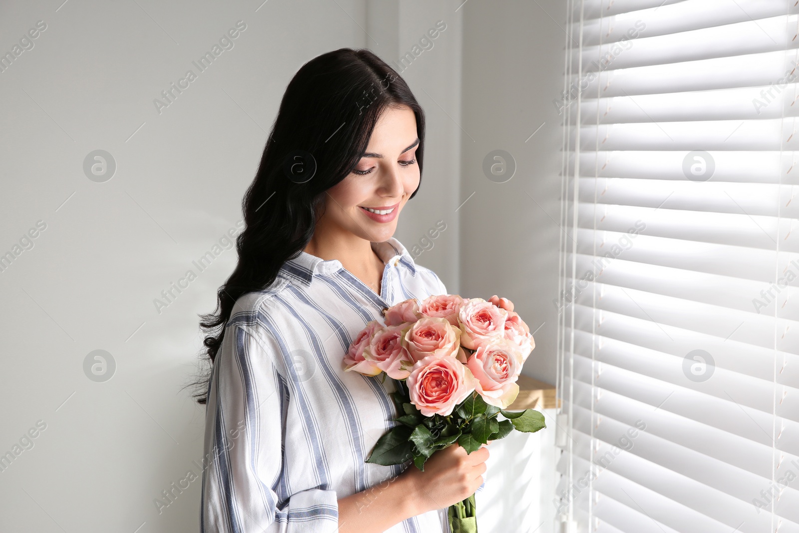 Portrait of smiling woman with beautiful bouquet near window at home Photo of Portrait of smiling woman with beautiful bouquet near window at home