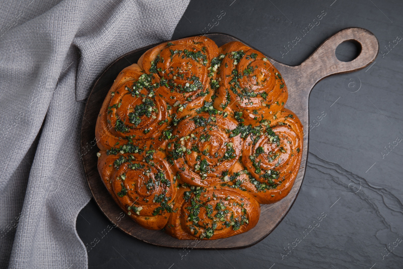 Traditional Ukrainian garlic bread with herbs (Pampushky) on black table, flat lay Photo of Traditional Ukrainian garlic bread with herbs (Pampushky) on black table, flat lay