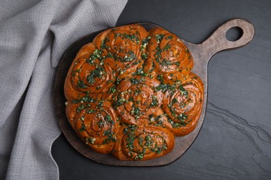 Traditional Ukrainian garlic bread with herbs (Pampushky) on black table, flat lay Photo of Traditional Ukrainian garlic bread with herbs (Pampushky) on black table, flat lay