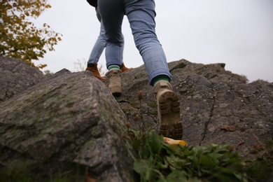 Couple wearing stylish hiking boots climbing up mountains, closeup Photo of Couple wearing stylish hiking boots climbing up mountains, closeup