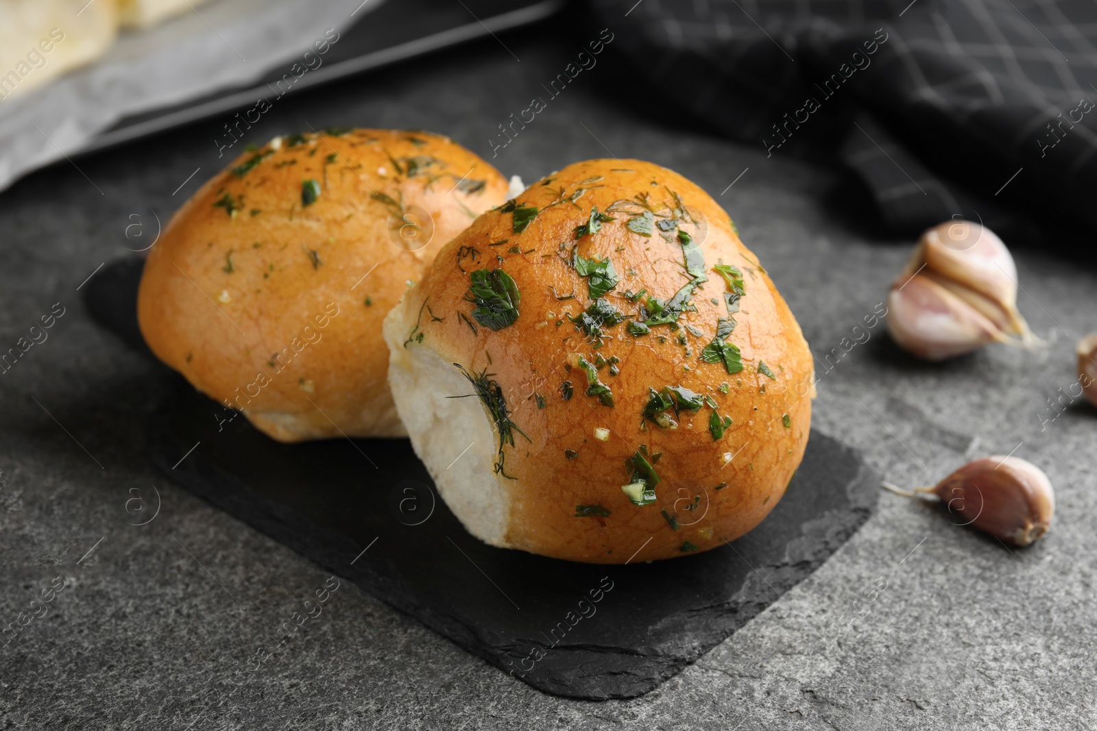 Traditional pampushka buns with garlic and herbs on grey table, closeup Photo of Traditional pampushka buns with garlic and herbs on grey table, closeup