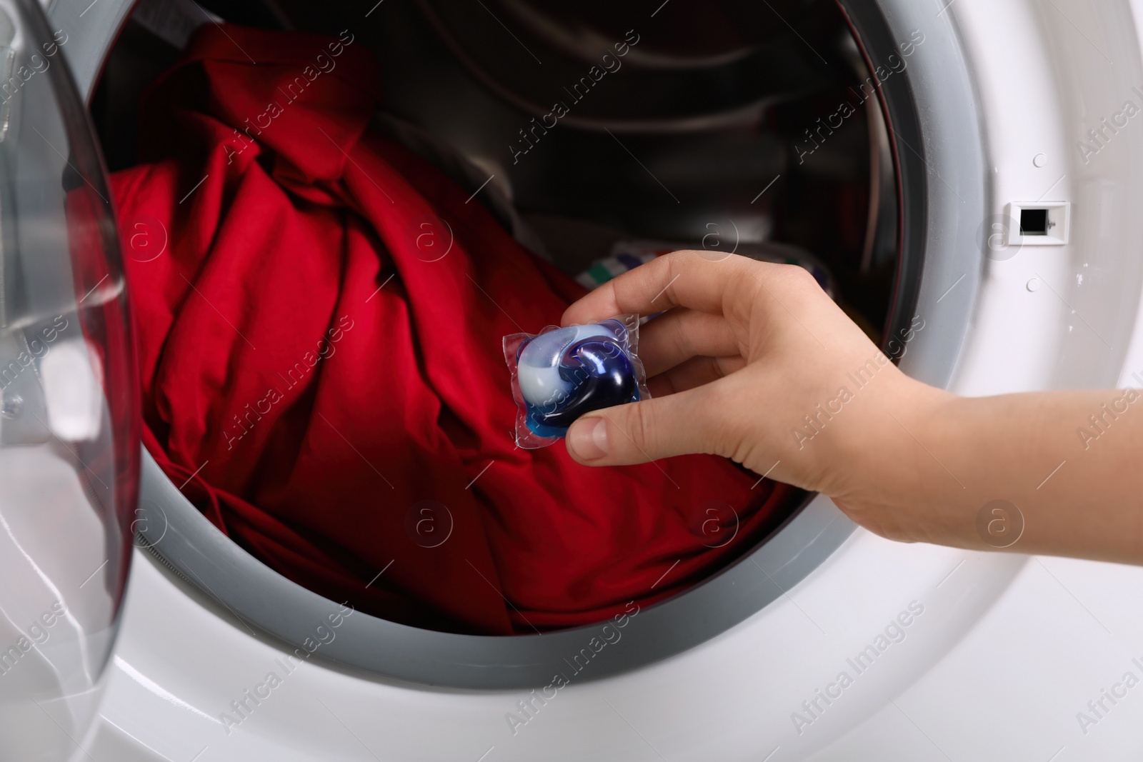 Woman putting laundry detergent capsule into washing machine, closeup Photo of Woman putting laundry detergent capsule into washing machine, closeup