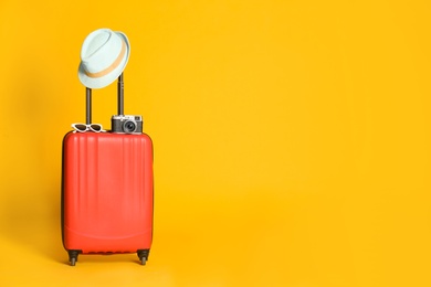 Travel suitcase with hat, camera and sunglasses on yellow background, space for text. Summer vacation Photo of Travel suitcase with hat, camera and sunglasses on yellow background, space for text. Summer vacation