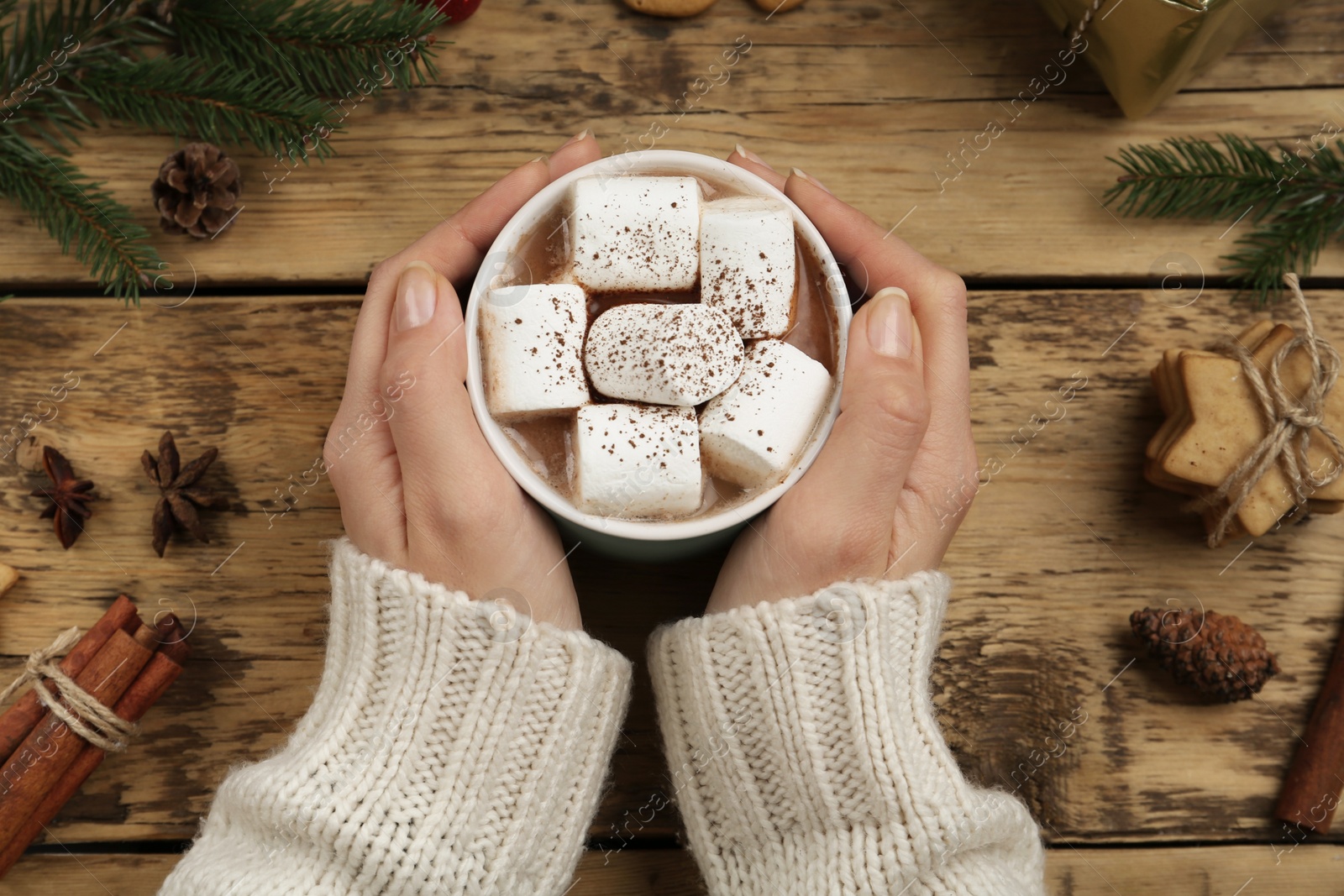 Woman with cup of delicious marshmallow cocoa at wooden table, top view Photo of Woman with cup of delicious marshmallow cocoa at wooden table, top view