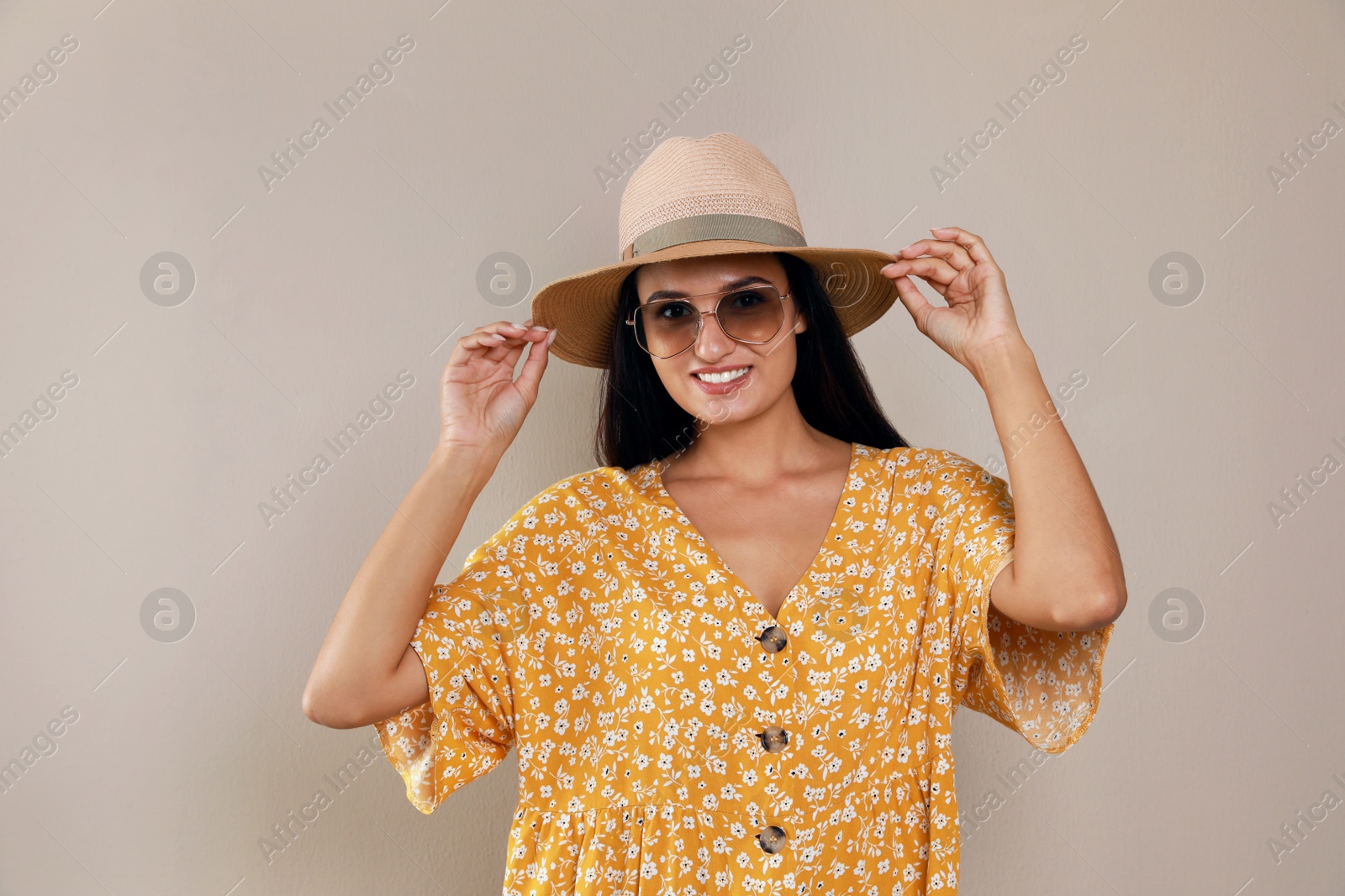 Photo of Beautiful young woman with straw hat and stylish sunglasses on beige background